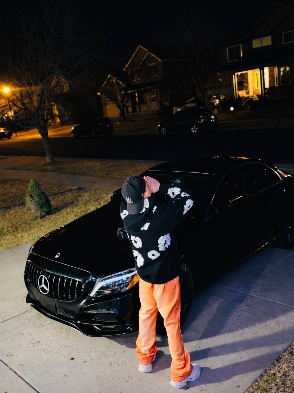 Milian junto a un Mercedes negro de noche en una calle iluminada