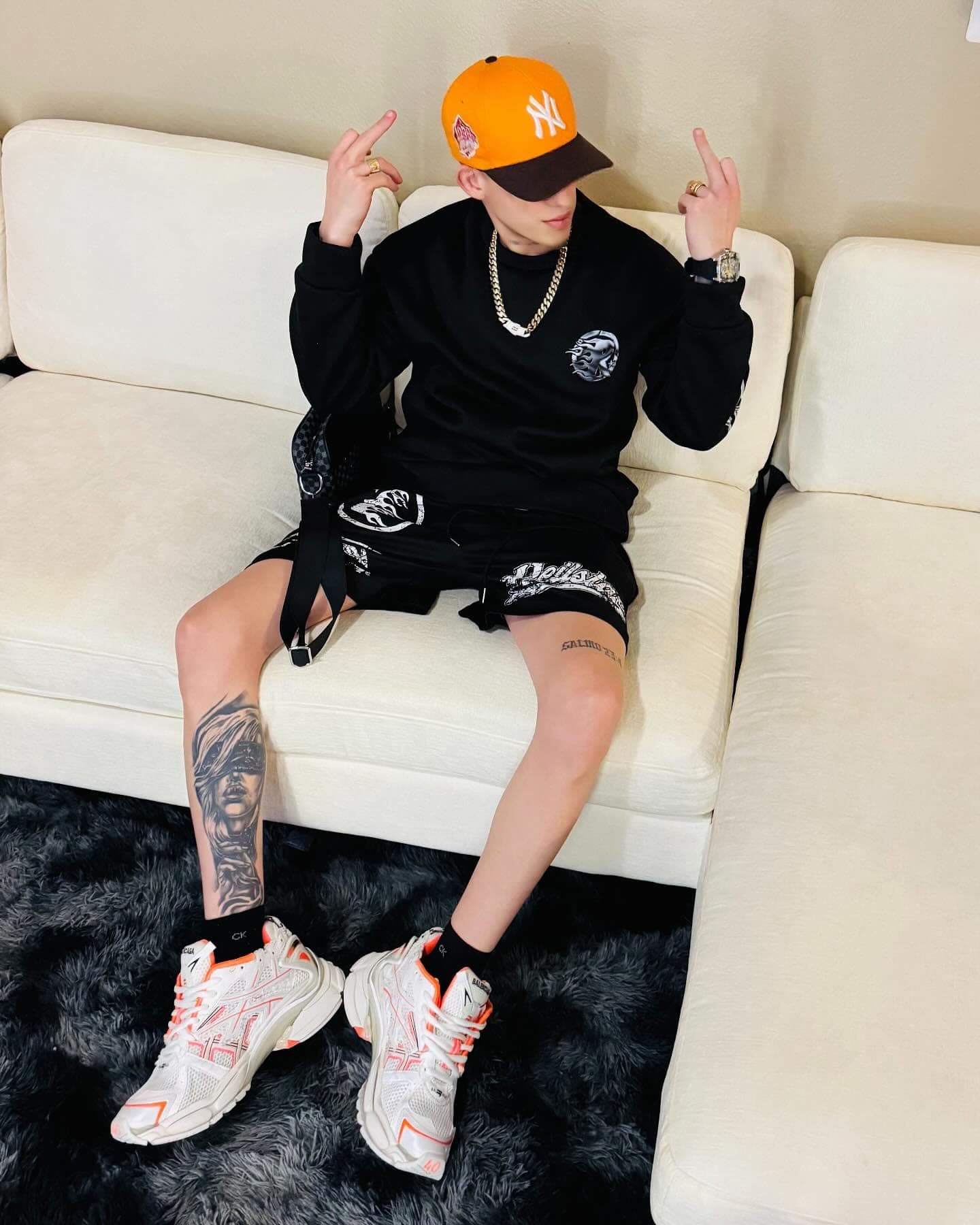 Milian sentado en un sofá blanco con gorra naranja